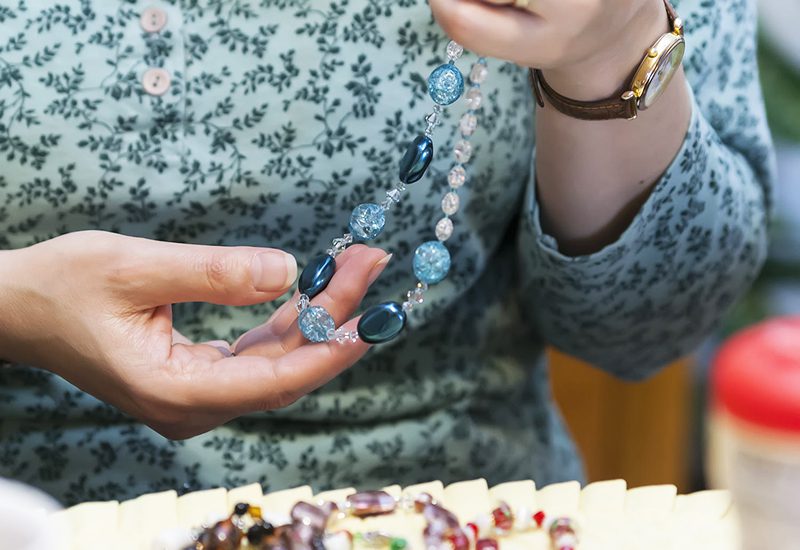 A Vietnamese woman examing a blue necklace of gemstones