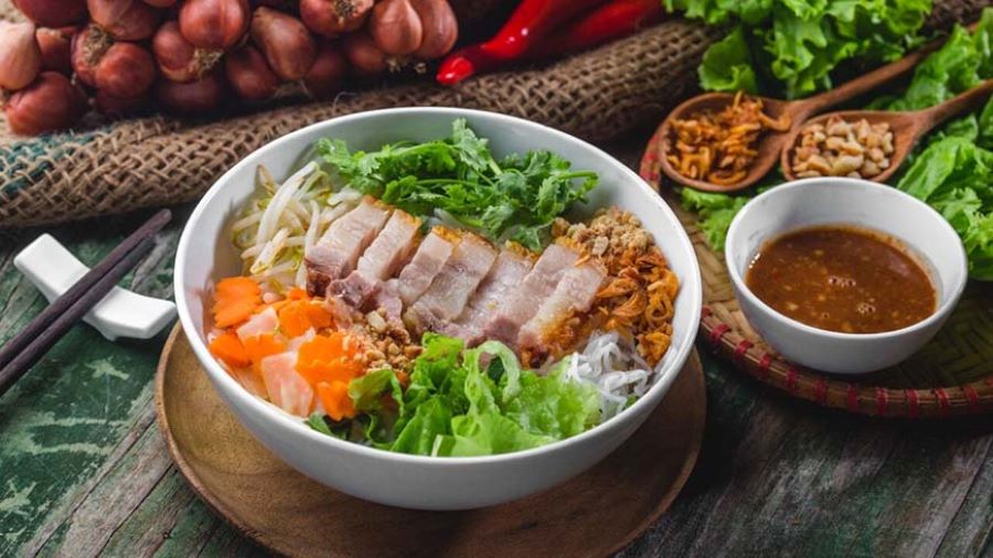 A vibrant Vietnamese noodle dish with fresh veggies, herbs, and pork.