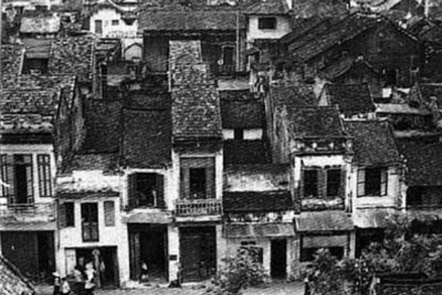 Black and white historical photo of a traditional Asian neighborhood with tiled rooftops and wooden houses, capturing the architectural charm of an older era.