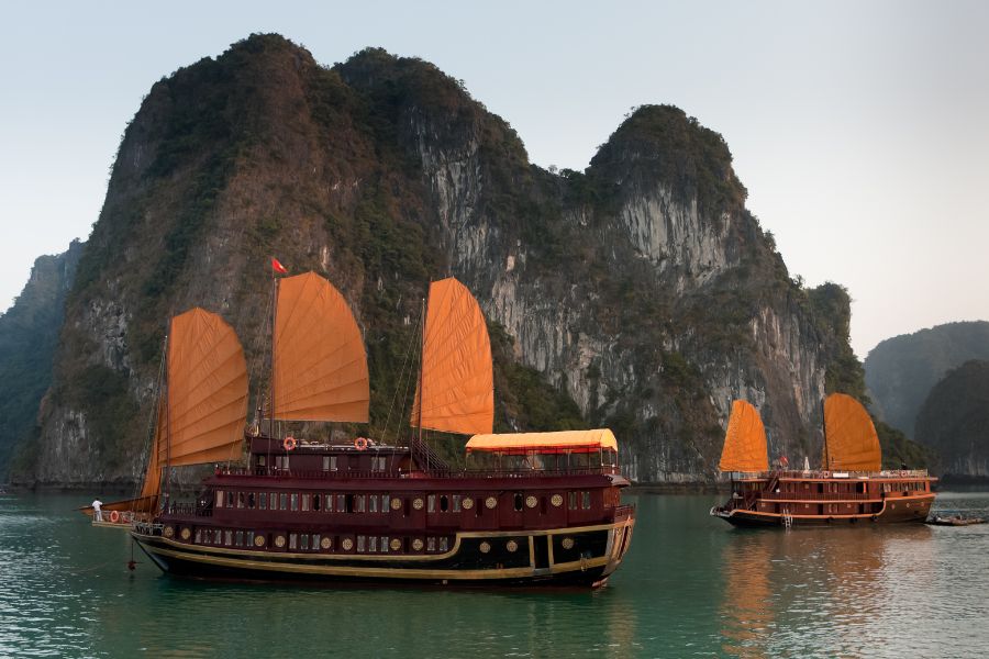 2 wooden junks during Vietnam Explorer tour, influenced by Indochina culture sailing admist Halong Bay
