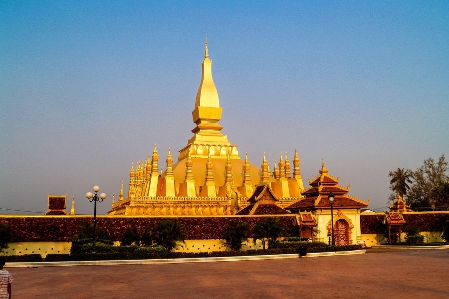 Pha That Luang shines with its golden stupa during sunset.