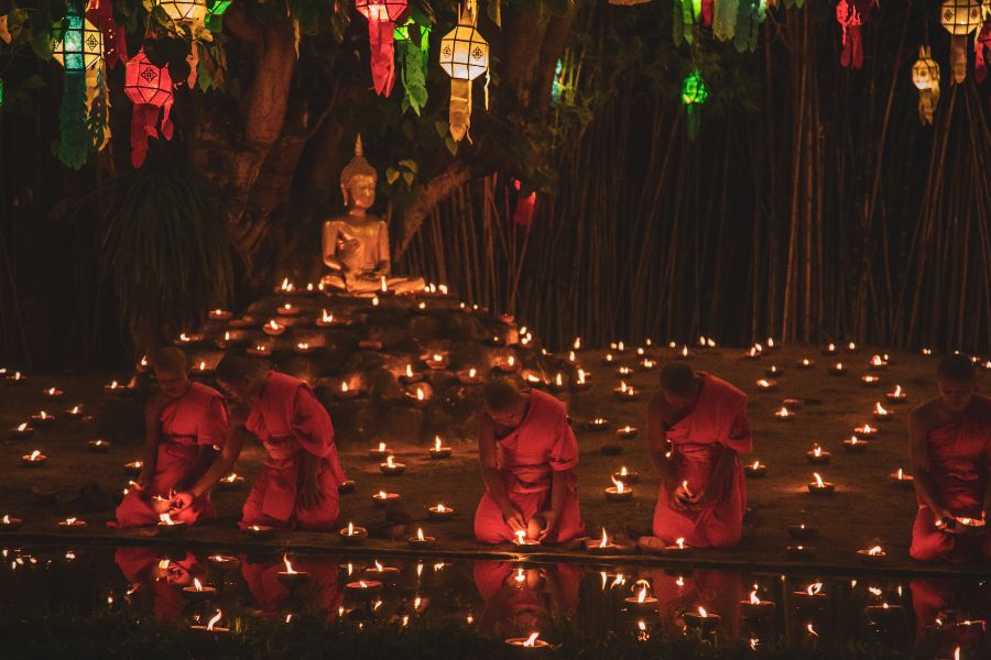 Monks in Chiang Mai lighting candles during Loy Krathong festival in Thailand.