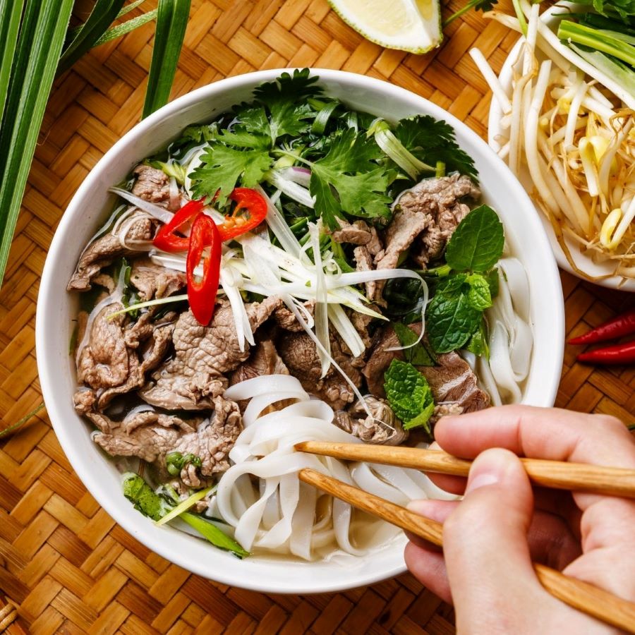 Pho noodle soup delights with rich broth, tender meat and fresh herbs