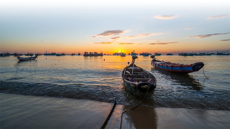 Phu Quoc’s fishing port awakens at sunrise, where boats drift through morning mist and the sea glows with light